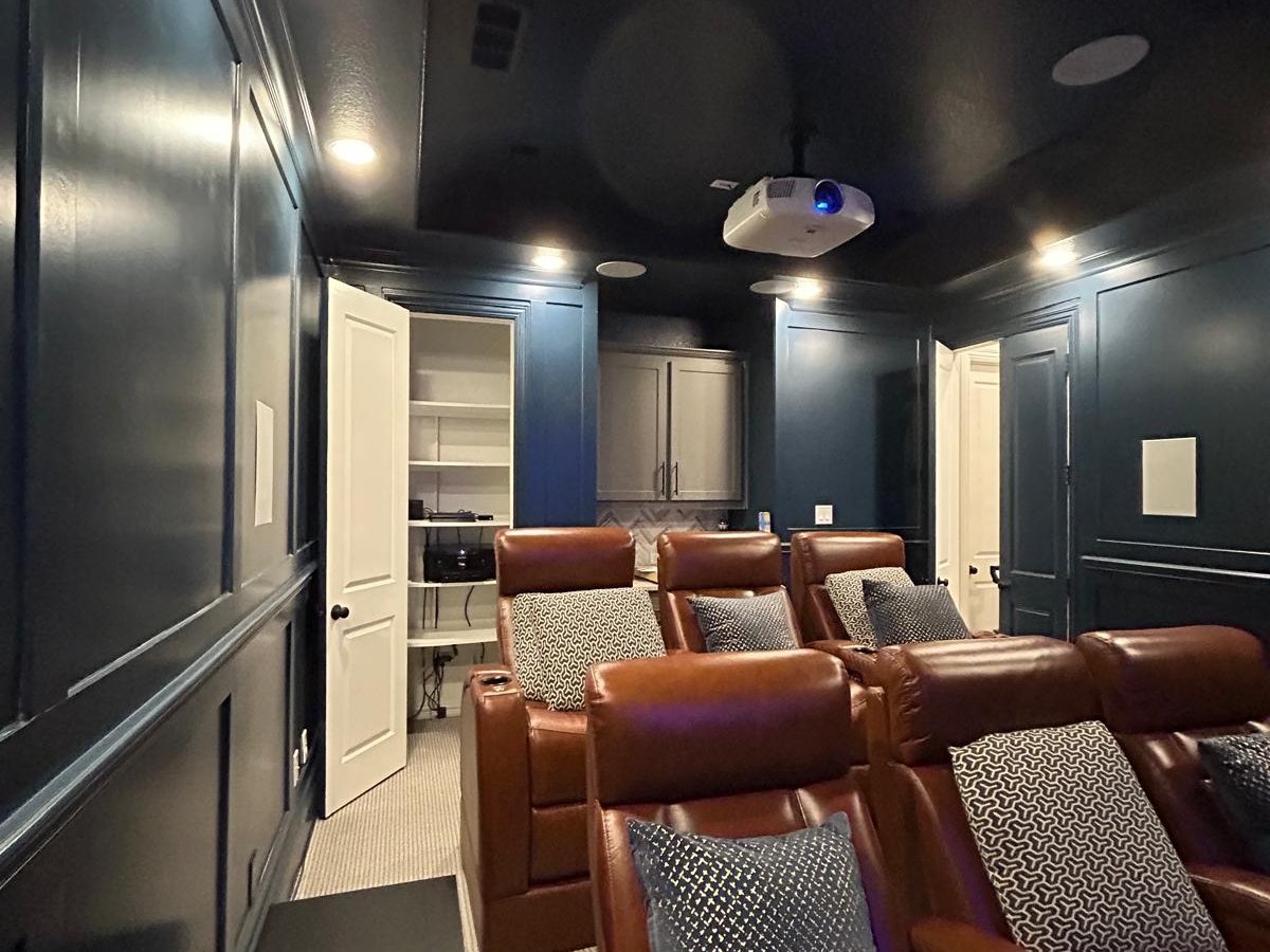 Custom home theater room with projector mounted on the ceiling and leather seating