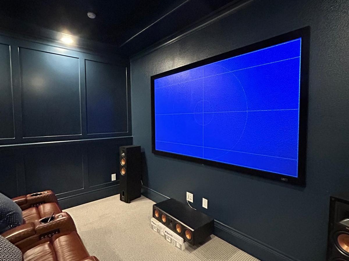 Home theater with screen and pair of Klipsch tower speakers flanking the screen